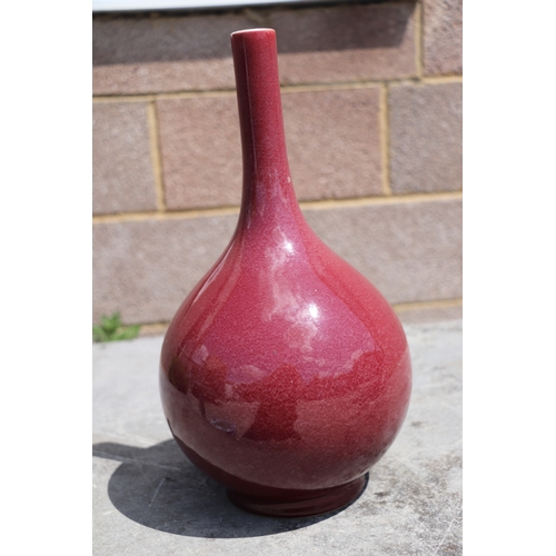 539 - A Chinese ox blood glazed bottle vase on hardwood stand, 34cms high.