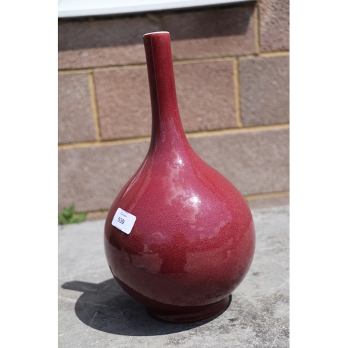 539 - A Chinese ox blood glazed bottle vase on hardwood stand, 34cms high.