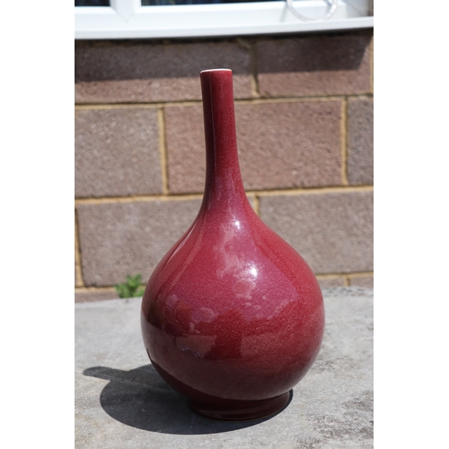 539 - A Chinese ox blood glazed bottle vase on hardwood stand, 34cms high.