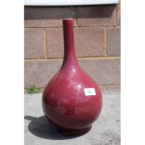 539 - A Chinese ox blood glazed bottle vase on hardwood stand, 34cms high.