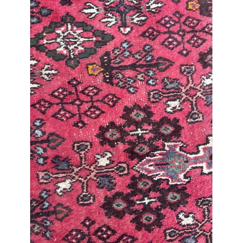 100 - A Persian hand knotted Shiraz carpet with central stylised gul within repeating borders, on a red gr... 