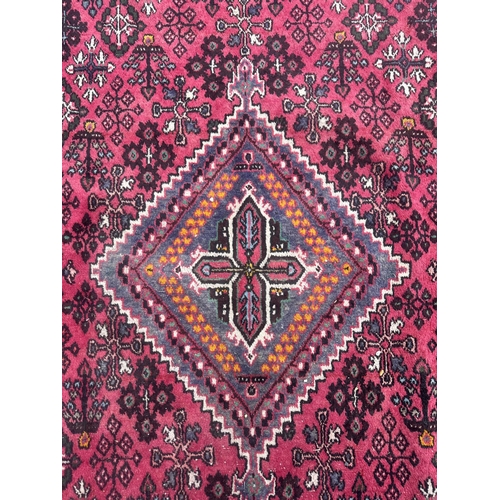 100 - A Persian hand knotted Shiraz carpet with central stylised gul within repeating borders, on a red gr... 