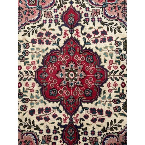 102 - A Persian hand knotted Tabriz carpet of traditional design with central floral gul on an ivory groun... 