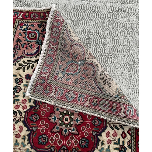 102 - A Persian hand knotted Tabriz carpet of traditional design with central floral gul on an ivory groun... 