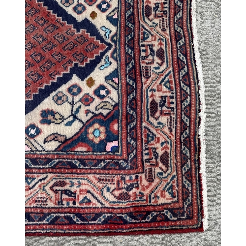 103 - A Persian Arak runner with repeating boteh in a central panel within blue & cream borders, on a red ... 