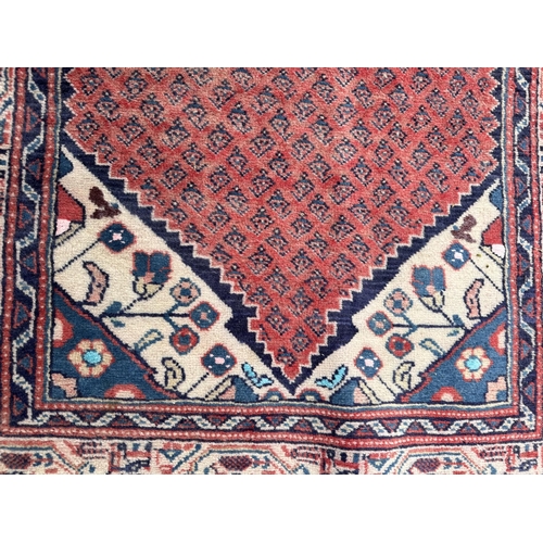 103 - A Persian Arak runner with repeating boteh in a central panel within blue & cream borders, on a red ... 