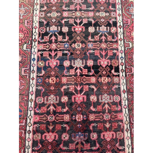 106 - A Persian Hamadan runner with repeating stylised floral design, on a red ground, 290 by 105cms.