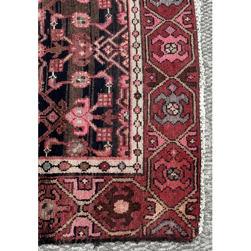 106 - A Persian Hamadan runner with repeating stylised floral design, on a red ground, 290 by 105cms.