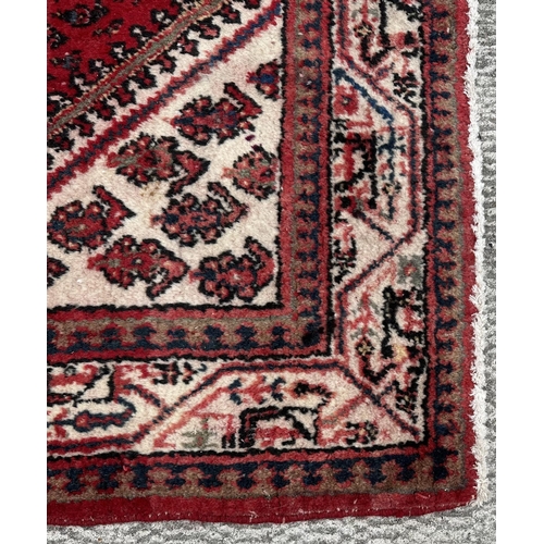 107 - A Persian Arak rug, the central diamond medallion within repeating boteh and stylised borders, on a ... 