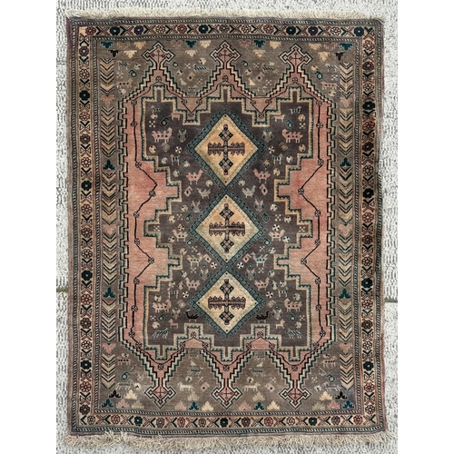 108 - A Persian hand knotted rug with three diamond medallions and stylised animals within a floral border... 