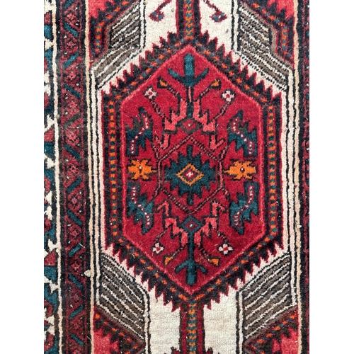 113 - A Persian hand knotted Qashqai runner with two red lozenges within a repeating stylised design, on a... 