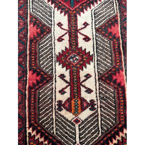 113 - A Persian hand knotted Qashqai runner with two red lozenges within a repeating stylised design, on a... 