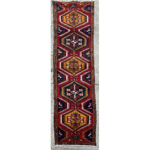 115 - A Persian hand knotted Azari runner with yellow and navy medallions, on a red ground, 410 by 85cms.