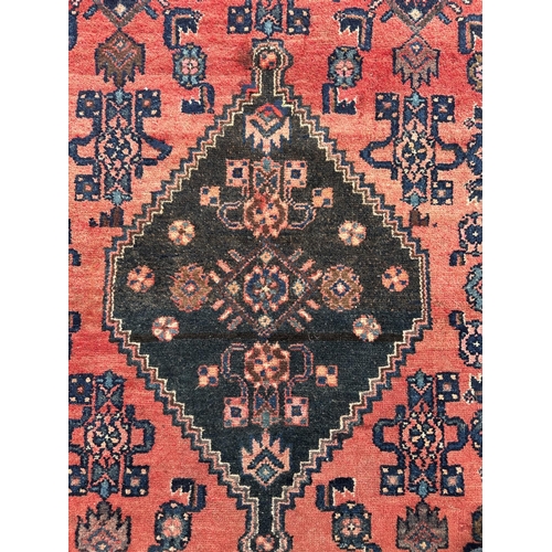 117 - A Persian hand knotted Hamadan rug with central diamond motif and blue spandrels, on a red ground, 1... 