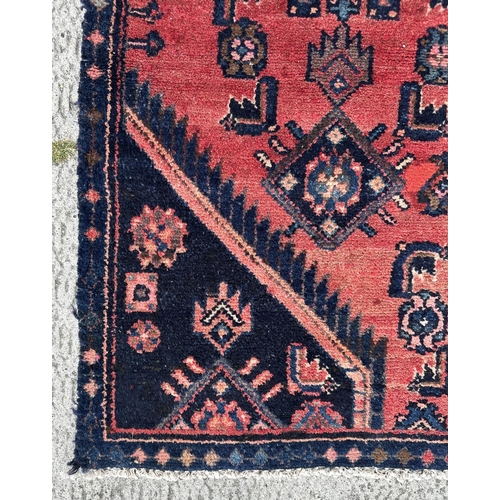 117 - A Persian hand knotted Hamadan rug with central diamond motif and blue spandrels, on a red ground, 1... 