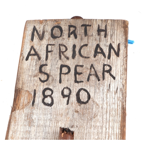 329 - A 19th century African tribal spear head mounted on a wooden plaque with inscription 'North African ... 