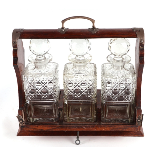 426 - A late Victorian / Edwardian oak three bottle tantalus, 31cms wide.Condition ReportNot marked.... 