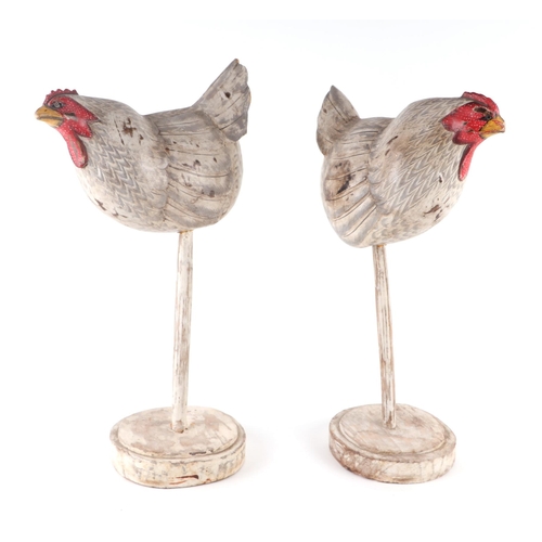 448 - A pair of Folk Art style distressed painted carved wooden models of chickens on stands, 47cms high (... 