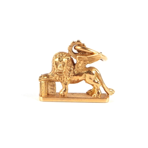 569 - An 18ct gold cross pendant; together with an 18ct gold charm in the form of a winged lion; and a yel... 