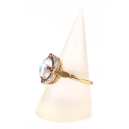 587 - A yellow metal mounted ring set with a central oval moonstone cabochon surrounded by diamonds and ru... 