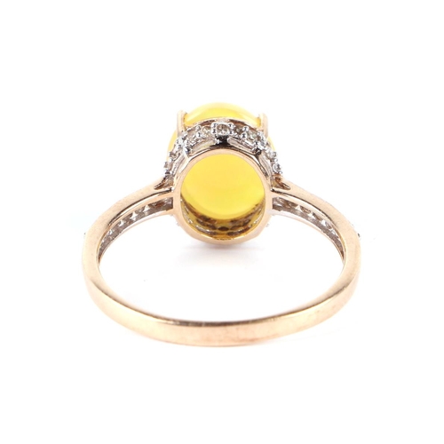 611 - A 9ct gold ring set with an oval yellow opal cabochon surrounded by diamonds and diamond set shoulde... 