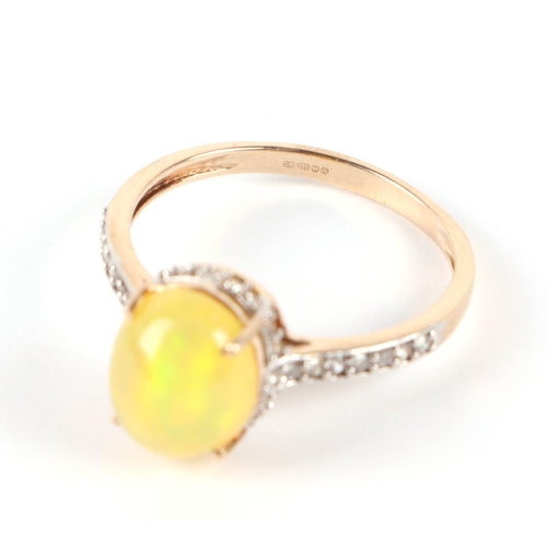 611 - A 9ct gold ring set with an oval yellow opal cabochon surrounded by diamonds and diamond set shoulde... 