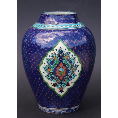 687 - A Palestine / Iznik pottery vase decorated with stylised flowers on a blue ground, 28cms high.