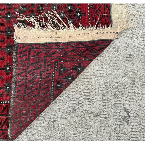 81 - A Persian Turkoman hand knotted rug with repeated design, on a red ground, 170 by 102cms.