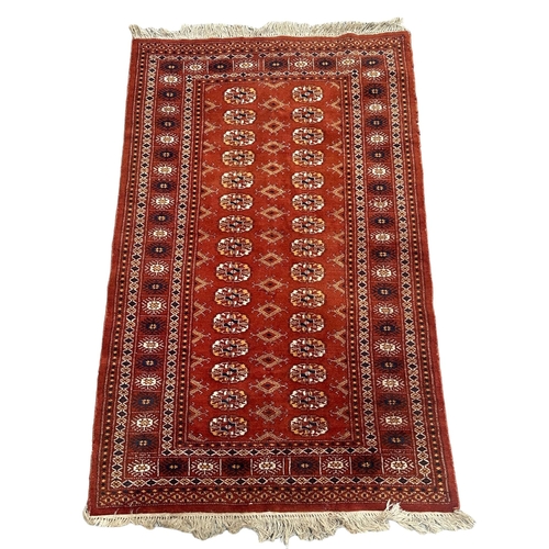 86 - A Persian Turkoman rug with repeat medallion design on a burnt orange ground, 92 by 120cms.