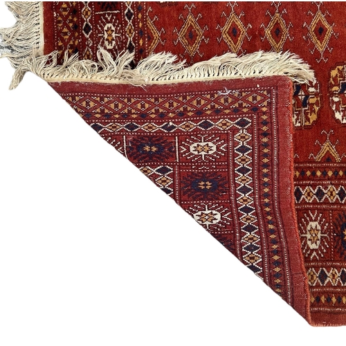 86 - A Persian Turkoman rug with repeat medallion design on a burnt orange ground, 92 by 120cms.