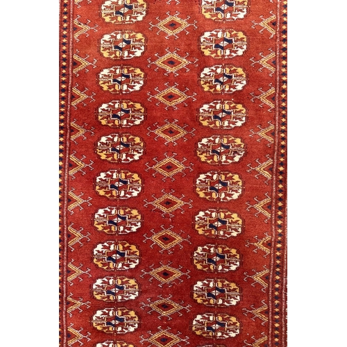 86 - A Persian Turkoman rug with repeat medallion design on a burnt orange ground, 92 by 120cms.