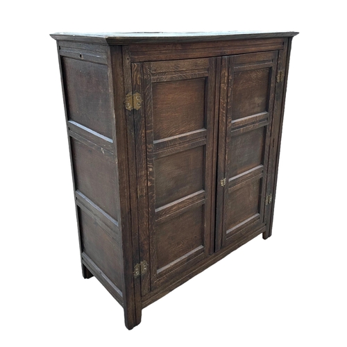 905 - An 18th / 19th century oak livery cupboard, the pair of panelled doors enclosing a shelved interior,... 