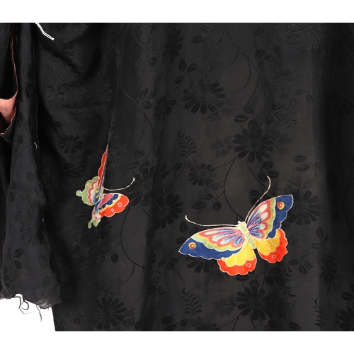 703 - A Japanese silk robe decorated with butterflies on a black ground.