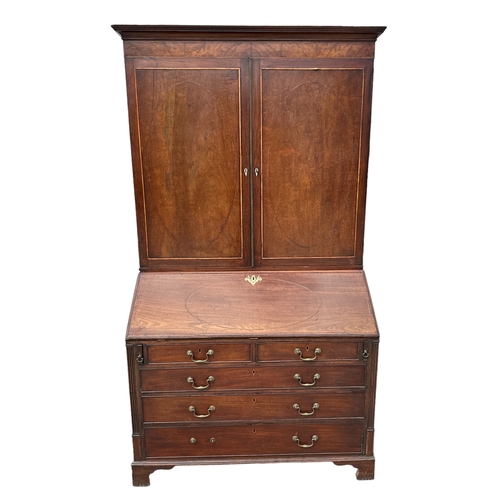 838 - A Georgian mahogany bureau bookcase, the pair of panelled doors enclosing a shelved interior above a... 