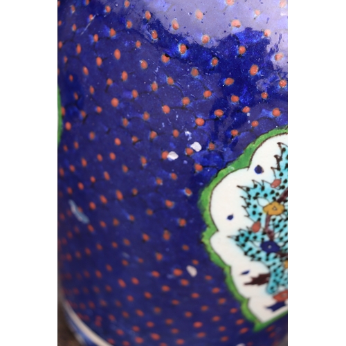 687 - A Palestine / Iznik pottery vase decorated with stylised flowers on a blue ground, 28cms high.