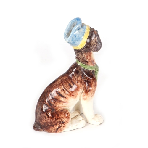 227 - A continental pottery figure in the form of a comical dog wearing a blue hat, 17cms high.