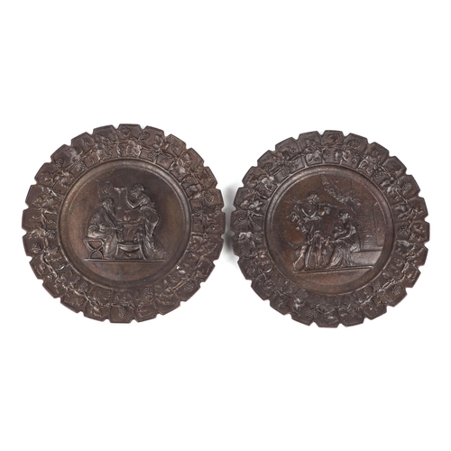 304 - A set of four cast iron plates decorated in relief with various scenes within a grape & vine border,... 