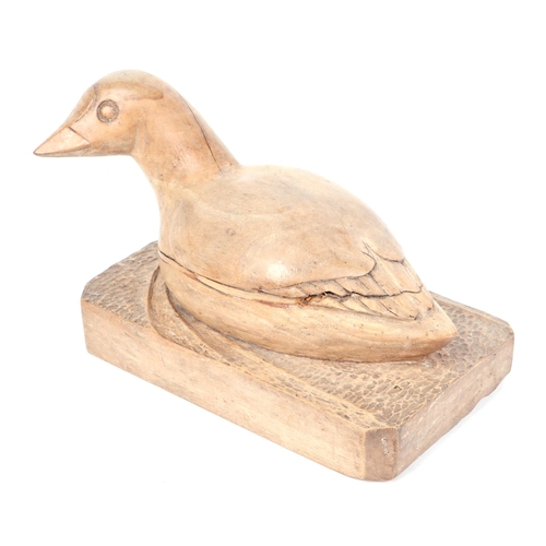 336 - Folk Art:  A wooden carving of a duck resting on a plinth.