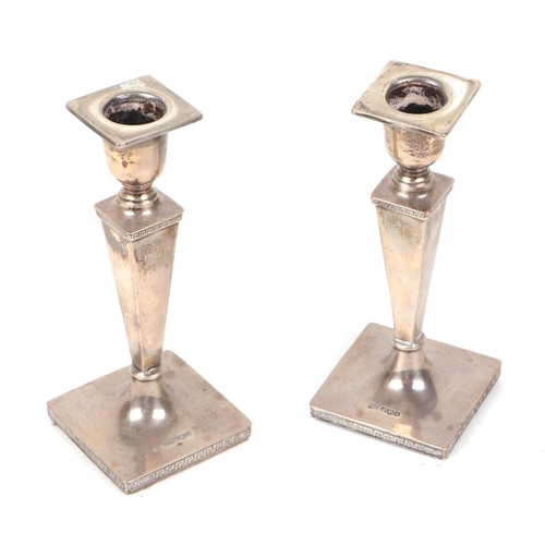 426 - A pair of George V silver weighted candlesticks with tapering column and Greek key decoration, Sheff... 