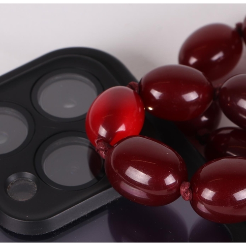 480 - A graduated set of cherry amber Bakelite type beads, the largest bead 3cms long.