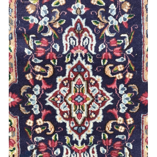 50 - A Persian Kirman hand knotted woollen rug with floral decorated central medallion, on a blue ground,... 