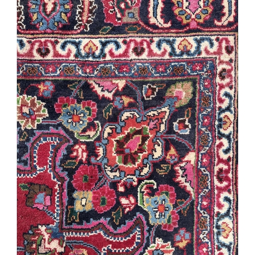 51 - A Persian Meshed carpet with central rosette medallion and floral borders, on a red ground, 390 by 2... 