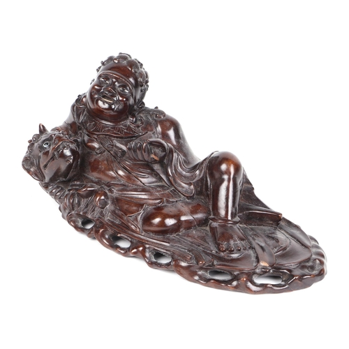 529 - A Chinese hardwood figural group depicting a recumbent man with a fo dog, 36cms wide.