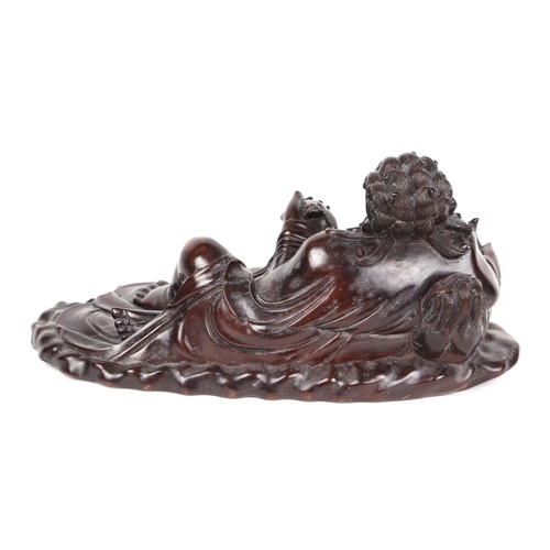 529 - A Chinese hardwood figural group depicting a recumbent man with a fo dog, 36cms wide.