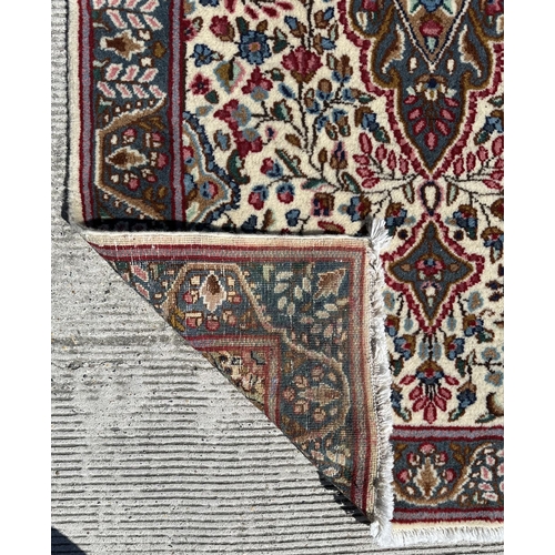 53 - A Persian Kerman rug with stylised floral design and central medallion with repeating foliate border... 