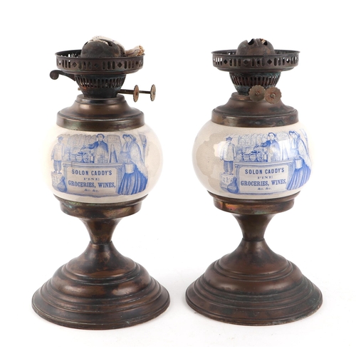 555 - A pair of brass and pottery advertising oil lamps, Solon Caddy's Fine Groceries, Wines & Co., 32cms ... 