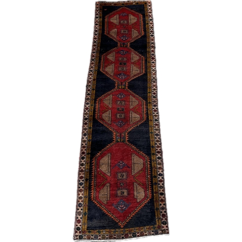 62 - A Persian Hamadan runner with four large linked red medallions, on a red ground, 365 by 100cms.