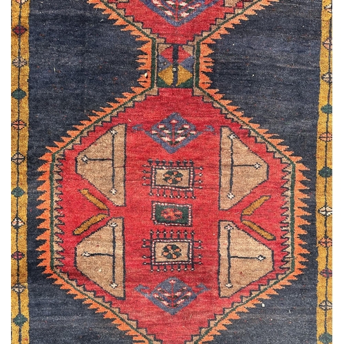 62 - A Persian Hamadan runner with four large linked red medallions, on a red ground, 365 by 100cms.