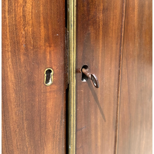 624 - An early 19th century mahogany linen press, the pair of panelled doors enclosing three linen slides ... 