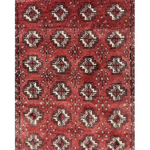 63 - A Persian Balouch rug with repeat stylised design, on a red ground, 180 by 100cms.